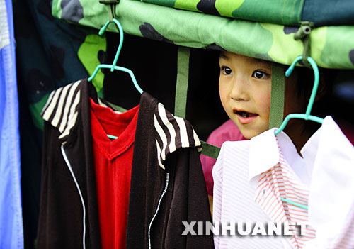 在四川省彭州市龙门山镇宝山村受灾群众安置点，7岁的邱艳波向帐篷外张望。