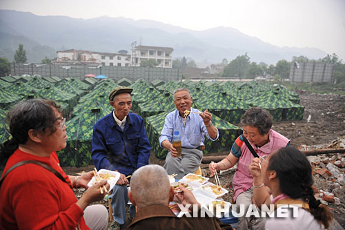 这是5月25日，在四川省彭州市龙门山镇宝山村受灾群众安置点，四户受灾群众在一起吃晚饭。