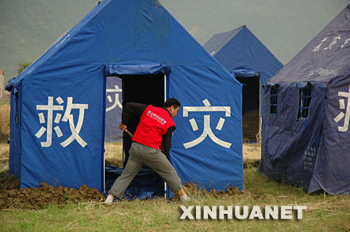 这是5月20日，自愿自费到地震灾区参加抗震救灾的唐山农民宋志永在安县晓坝镇受灾群众安置点的帐篷边挖掘排水沟。