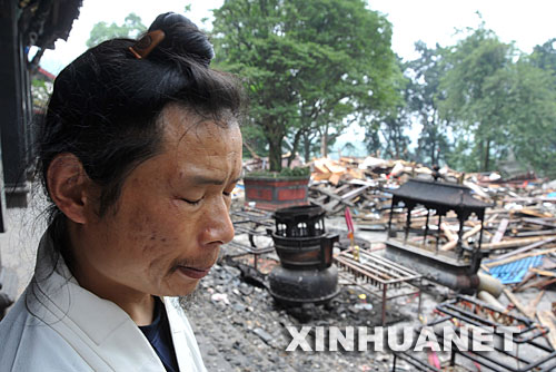 5月26日，在都江堰景区二王庙，一名道士面对废墟，痛苦地闭上双眼。