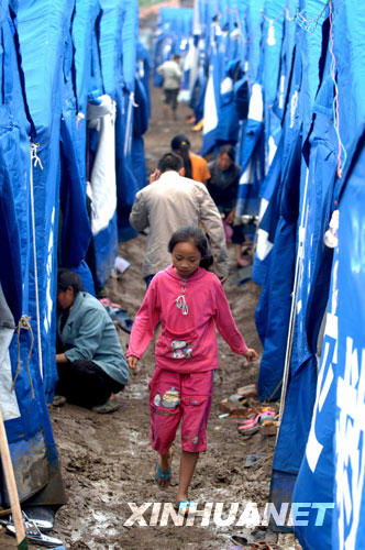 5月29日，四川北川县擂鼓镇安置点的一名孩子从帐篷间的泥地上走过。