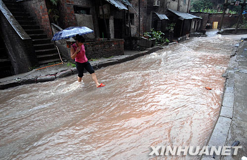 5月28日，重庆一位市民涉水穿越雨水流淌的公路。