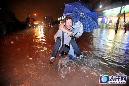 廣州白雲區德康路路面的積水已經淹到了大腿，一位丈夫背著自己的妻子穿過馬路。