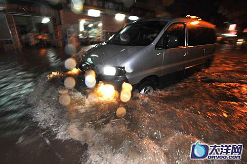在廣州白雲區德康路，路面的積水已經淹到了大腿，一輛車正在經過。