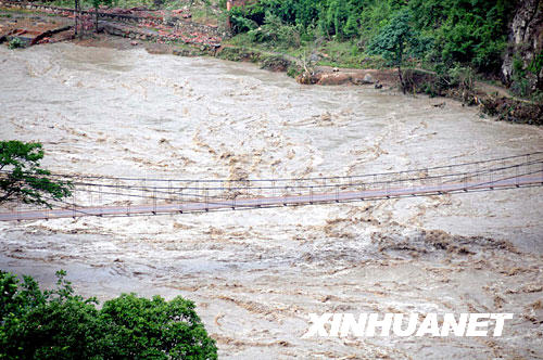 6月10日，唐家山堰塞湖泄洪后，滚滚浊浪从北川县通口镇的铁索桥下流过。通口镇是距离唐家山堰塞湖最近的一个镇