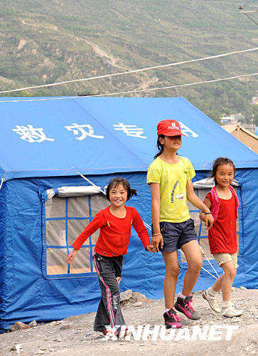 6月10日，阿坝州儿童福利院的三个孩子走在帐篷营地前