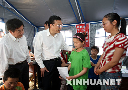 5月19日，中共中央政治局常委、國務(wù)院副總理、國務(wù)院抗震救災(zāi)總指揮部副總指揮李克強(qiáng)在四川地震災(zāi)區(qū)察看災(zāi)情，指導(dǎo)協(xié)調(diào)抗震救災(zāi)工作。這是李克強(qiáng)在臨時(shí)課堂里安慰在地震中失去雙親的12歲北川女孩王婷婷（著綠衣者）。 新華社記者 蘭紅光 攝 