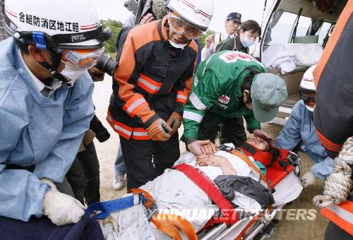 6月14日，救援人員在日本岩手縣將一名在地震中受傷的居民送上救護車。