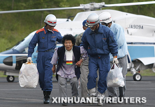 6月14日，在日本北部的宮城縣栗原市，救援人員護送一名從被困地帶疏散出來的老人離開直升飛機。