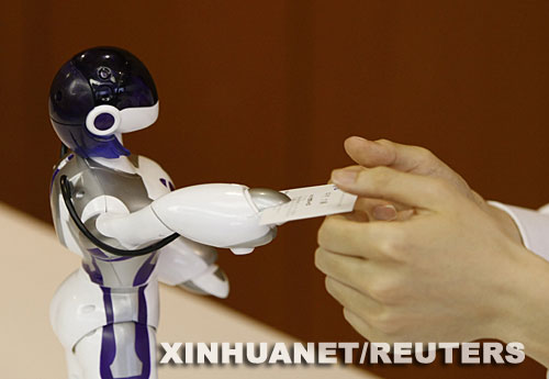 6月16日，日本世嘉玩具公司推出的新型机器人在东京举行的展示活动上向一名男士递交名片。这种机器人具有女性的体形，不仅会走路，还会跳舞和与人亲吻。预计从今年9月26日开始在日本国内出售，售价每个1.8万日元（约合166美元） 新华社/路透 