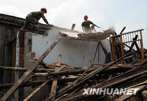 抗震救灾官兵帮助绵竹市板桥镇村民清理危房瞬间（6月19日摄）。