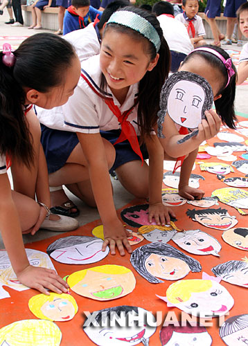 6月22日，一名学生准备把自己的“笑脸”贴到奥运五环里。 为迎接6月23日国际奥林匹克日，安徽省淮北市黎苑小学开展最美“笑脸”迎奥运活动，学生们把自己画的“笑脸”贴在奥运五环里，由老师和学生组成的评委对作品进行投票评奖。 新华社发(李博 摄) 