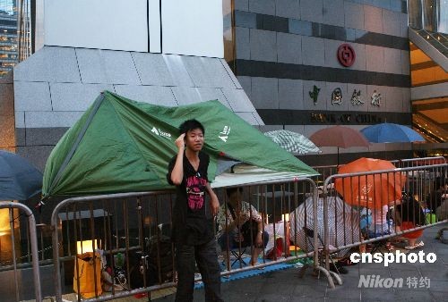 离中银香港发行面额二十元港币的奥运纪念钞票还有两天时间，香港中银大厦外已有不少市民排队等候，队伍中不乏伞阵和帐篷。