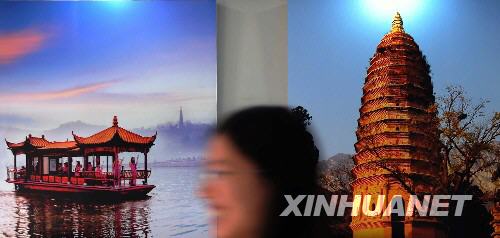 7月28日，一名志愿者从奥运村里张贴的中国文化旅游招贴画前走过。