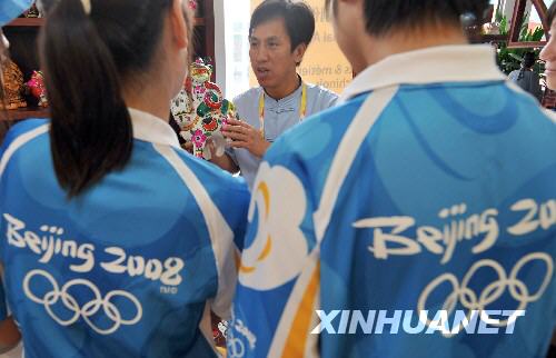 7月28日，来自陕西的泥人艺术家胡新明在奥运村里向参观者介绍泥人作品。
