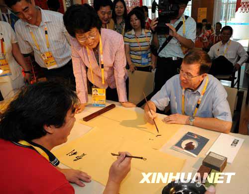  7月27日，国际奥委会奥运会执行主任费利（右）在青岛奥运村国际区中国民俗文化展厅学写毛笔字。