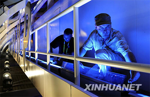 来自德国的灯光技师林格·施托希（右）和同事在固定灯管线路（7月28日摄）。 新华社记者张铎摄