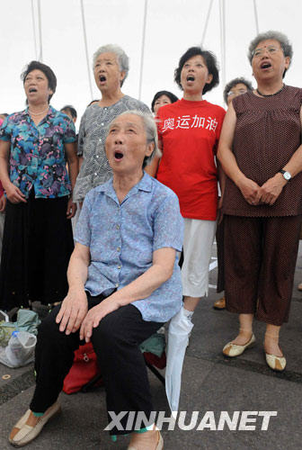 7月30日，在青岛音乐广场，一位年过七旬的老人和大家一起唱奥运歌曲。