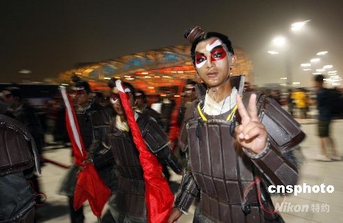 7月30日，北京奥运会开幕式在“鸟巢”进行彩排后，于夜幕中走出国家体育场的古装演员作出胜利手势。