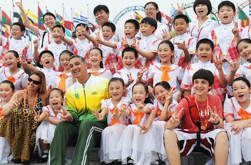 8月4日，北京市中关村三小“同心结”合唱团的学生在北京奥运村升旗广场与巴西代表团成员合影。