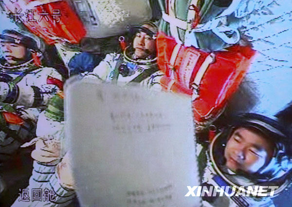 9月28日，航天员刘伯明（右）在神舟七号载人飞船上轻松地向地面控制中心工作人员展示书写的文字（摄于北京航天飞行控制中心大屏幕）。当日中午，神舟七号返回舱舱门已经关闭，神七返回阶段开始。