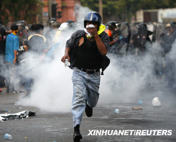 10月7日，在泰國首都曼谷的國會大院附近，一名反政府示威者逃離警方施放催淚瓦斯的現場。