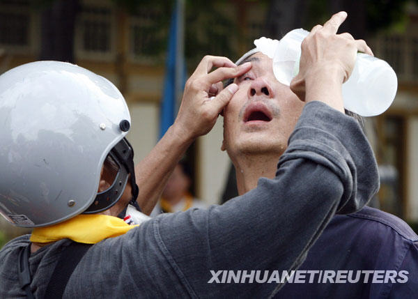  10月7日，在泰國(guó)首都曼谷的國(guó)會(huì)大院附近，一名反政府示威者在警察施放催淚彈后幫同伴清洗眼睛。 