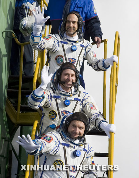 10月12日，在哈萨克斯坦的拜科努尔发射场，国际空间站第十八长期考察组的俄罗斯宇航员尤里·隆恰科夫（前）、美国宇航员迈克·芬克（中）和世界第六位太空游客、美国电脑游戏开发商理查德·加里奥特在登上飞船前向人们挥手。当日，国际空间站第十八长期考察组三名宇航员乘坐俄罗斯“联盟TMA-13”载人飞船升空，前往国际空间站。 新华社/路透 