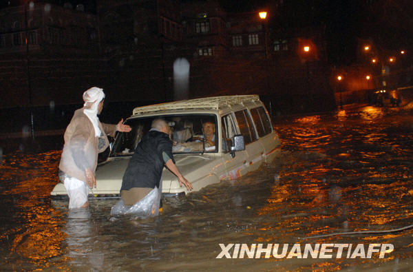 10月24日，在也门首都萨那一条被洪水淹没的路上，当地人帮助一名困在车里的外国游客。据也门通讯社当天报道，近几日持续暴雨引发的洪水和泥石流在也门东部的哈德拉毛省和马哈拉省造成46人死亡或失踪，数百座民房被冲毁，许多基础设施遭到破坏。 新华社/法新 