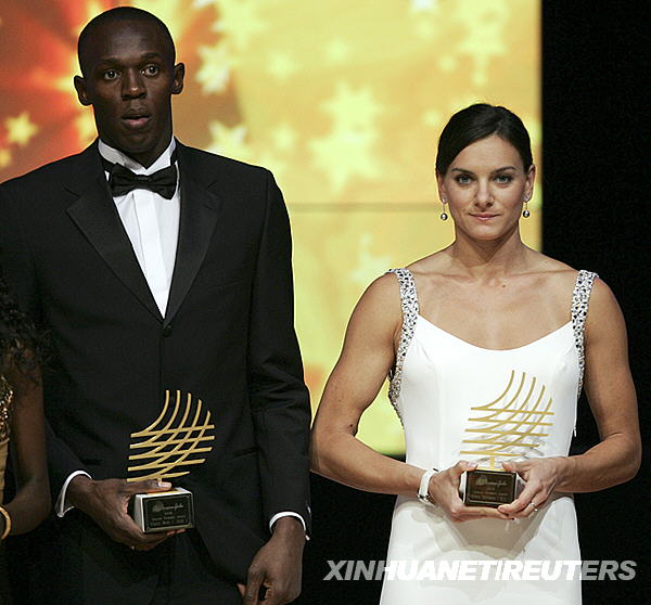  11月23日，牙买加短跑选手博尔特（左）和俄罗斯女子撑杆跳选手伊辛巴耶娃在颁奖仪式上手捧2008年度奥林匹克特别奖奖杯。