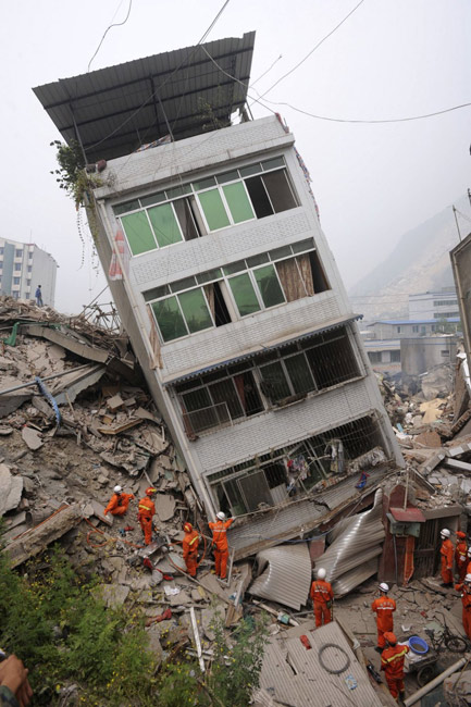5月17日，四川省北川县，搜救人员正在一幢倾斜的建筑物附近寻找幸存者。