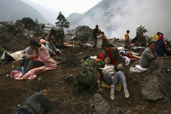 2008年5月13日，四川省北川县的地震受伤者坐在碎石上。 