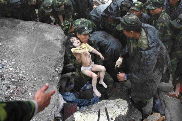 2008年5月13日，士兵们从北川县地震碎石中救出一名儿童。