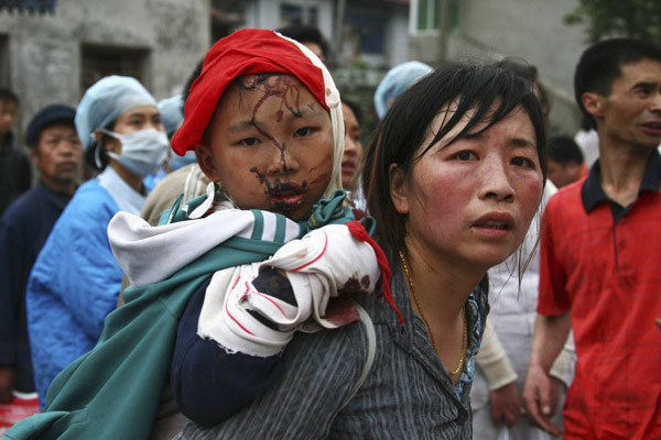 2008年5月13日，北川县地震后，一名女子背着一名获救的孩子。
