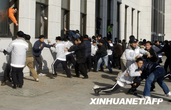 1月3日，在韩国首都首尔，警察（穿灰白色上衣者）阻止反对党成员爬窗进入国会。韩国主要反对党民主党议员自2008年12月26日起占据了国会大会议厅内的议长座位，以阻止执政的大国家党单方面通过一系列有争议法案。