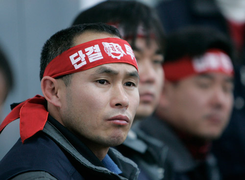 1月12日，韩国双龙汽车工会在平泽工厂举行的记者发布会上称，双龙汽车的倒闭是作为国家基础产业的汽车技术泄露问题，并指责大股东上汽集团没有给予足够的资金支持。头巾上的韩文字写着“团结、斗争”。