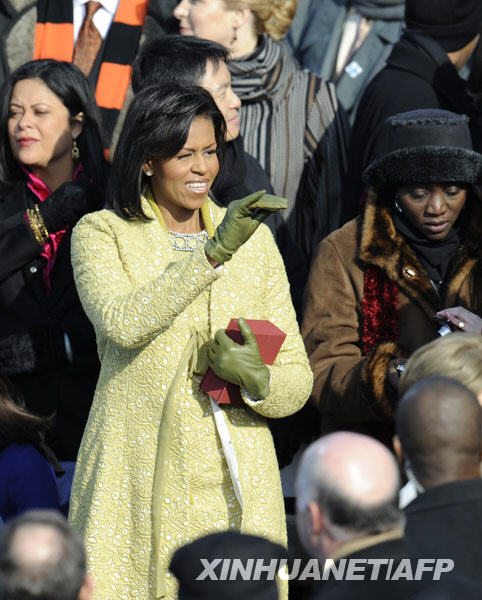 1月20日，在美国首都华盛顿，美国新“第一夫人”米歇尔·奥巴马（中）在总统就职典礼上挥手致意。当日，新“第一夫人”选择黄色外套和连衣裙出席总统就职典礼，得到时尚人士大赞。时尚专业人士说，美国政界女性传统着装颜色是红、白和蓝，米歇尔选择黄色，别出心裁。在世界许多地方，黄色象征希望和乐观。 