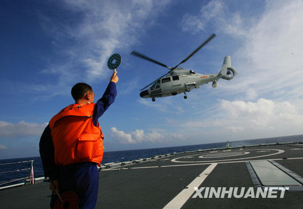 “广州”舰引导员在甲板上引导直升机起降（2月23日摄）。