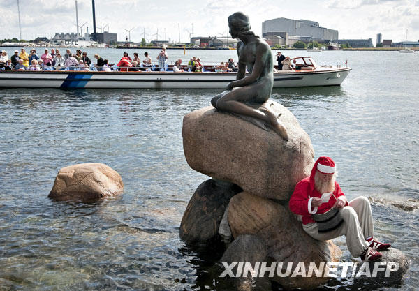 7月21日，一名打扮成圣诞老人的男子倚靠在丹麦首都哥本哈根的美人鱼铜像下