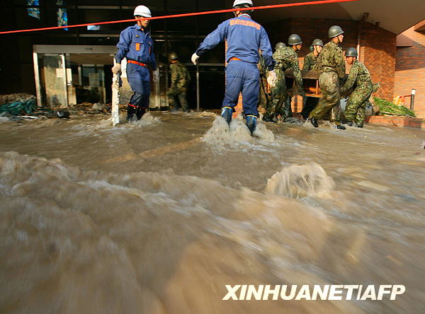 7月22日，在日本本州岛西部山口县防府市，救援人员在大水中寻找失踪者
