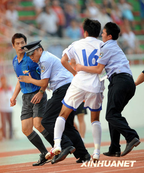 7月26日，天津队球员在追打主裁判何志彪（左）时被警察阻拦。当日，在全运会男子足球甲组北京队与天津队的比赛结束后，天津队球员由于对裁判的判罚不满，追打主裁判何志彪。 