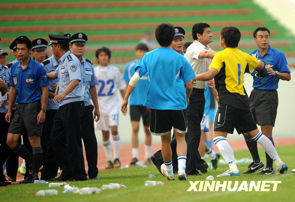 7月26日，主裁判何志彪（左一）在警察保护下离场。当日，在全运会男子足球甲组北京队与天津队的比赛结束后，天津队球员由于对裁判的判罚不满，追打主裁判何志彪。 