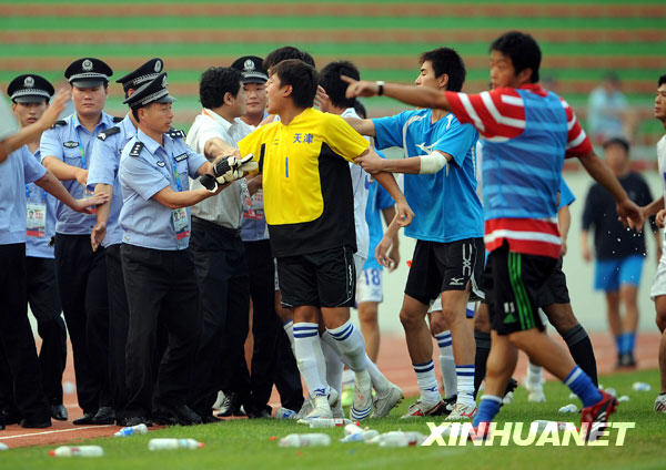 7月26日，警察劝阻情绪激动的天津队守门员里根（中）。当日，在全运会男子足球甲组北京队与天津队的比赛结束后，天津队球员由于对裁判的判罚不满，追打主裁判何志彪。 