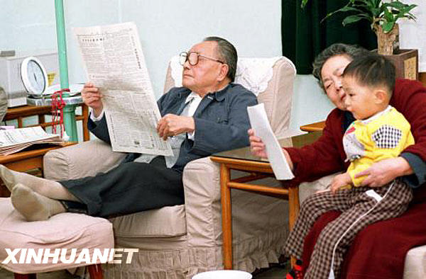 这是退休后的邓小平在家中阅读报纸。一旁，卓琳在为孙子讲故事。 