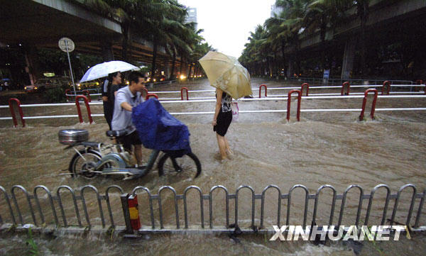  8月6日，行人在海口市区街道涉水行走。