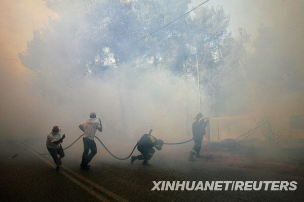 8月23日，在希腊首都雅典东北部约25公里处，消防员与山林大火搏斗。希腊首都雅典北部的山林大火23日继续燃烧，数千公顷的森林和庄稼以及数十间民宅被烈火吞噬。