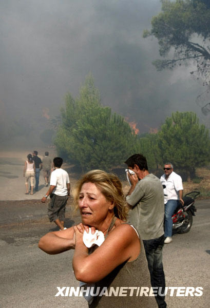 8月23日，在希腊首都雅典北部郊区，一名妇女在山林大火逼近她的房屋时哭喊。希腊首都雅典北部的山林大火23日继续燃烧，数千公顷的森林和庄稼以及数十间民宅被烈火吞噬。