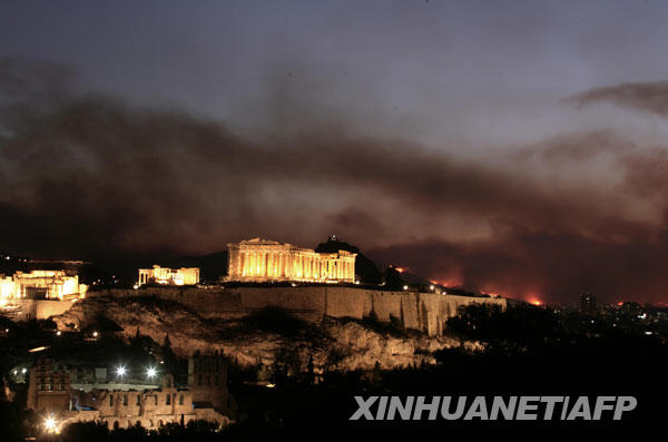 8月23日，在希腊首都雅典，雅典卫城后面的山林大火冒起浓烟。希腊首都雅典北部的山林大火23日继续燃烧，数千公顷的森林和庄稼以及数十间民宅被烈火吞噬。