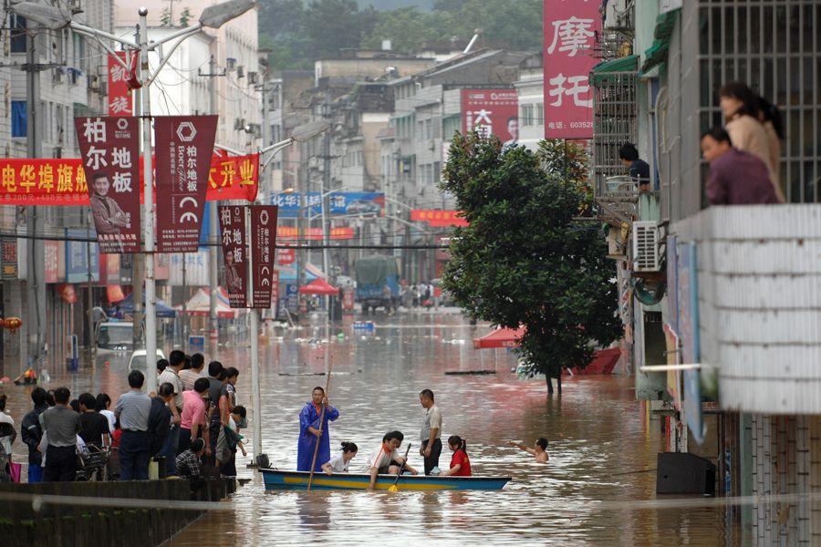 6月15日，浙江开化，两位村民在被水淹的开化县华埠镇撑船转移受灾群众。 新华社记者 鞠焕宗 摄