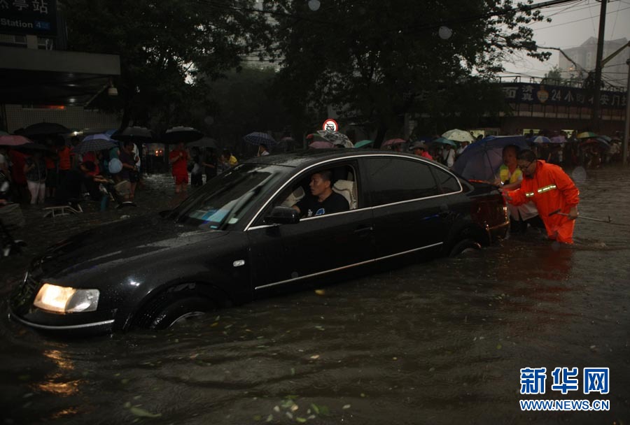 6月23日，在北京陶然亭地鐵站附近，市政人員和市民在積水的路段上推行一輛熄火的轎車。當日下午，北京遭遇強雷雨天氣。此次降水過程中，北京市大部分地區以大雨為主，局部地區降水達到大暴雨級別。城區部分路段因路面積水道路基本中斷。新華社發（李方宇攝） 